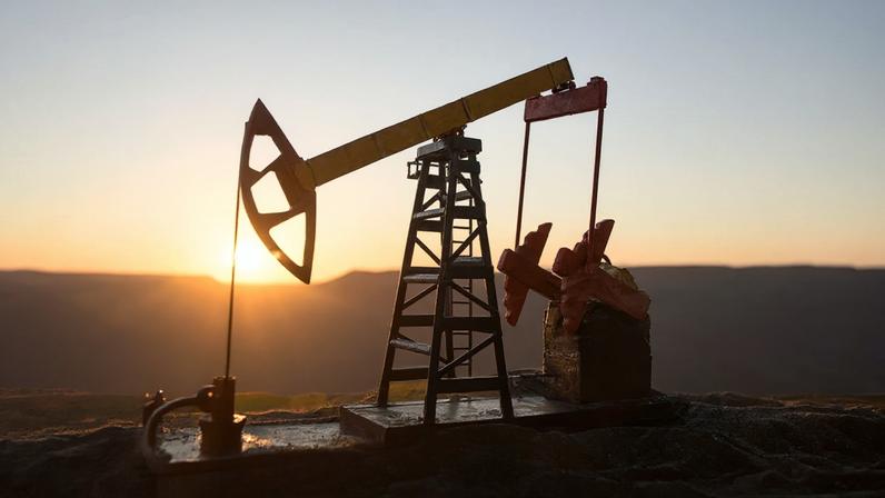 Bomba de óleo e fábrica de refino de petróleo ao pôr do sol