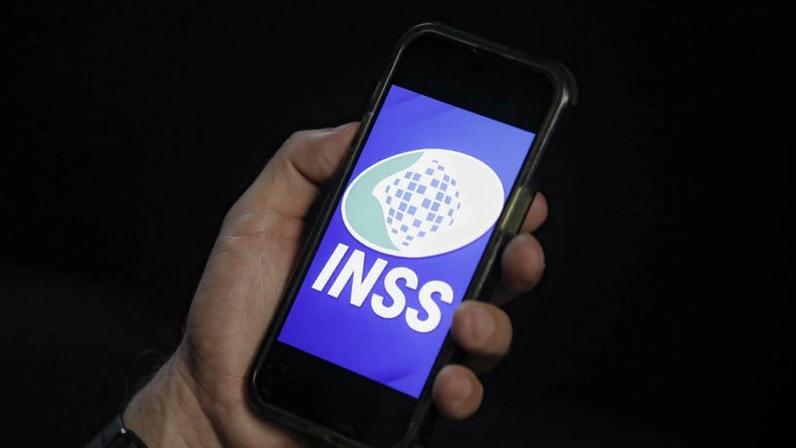 INSS pega o valor original devido e o multiplica pelo fator correspondente do índice; na imagem, uma pessoa usa o aplicativo do Instituto