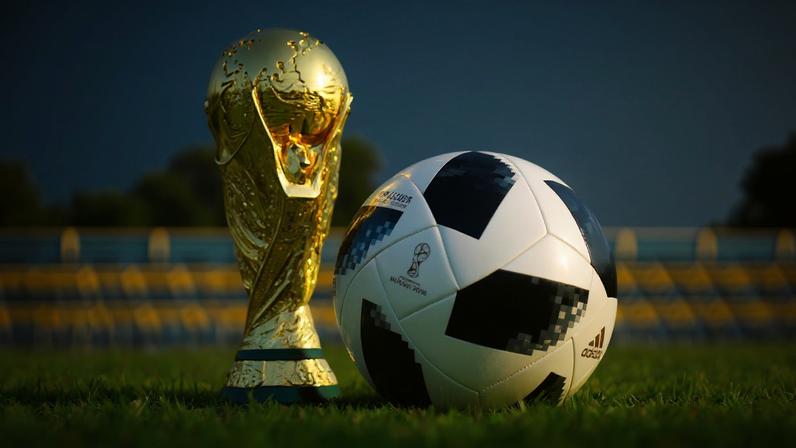 Taça da copa do mundo ao lado de uma bola de futebol