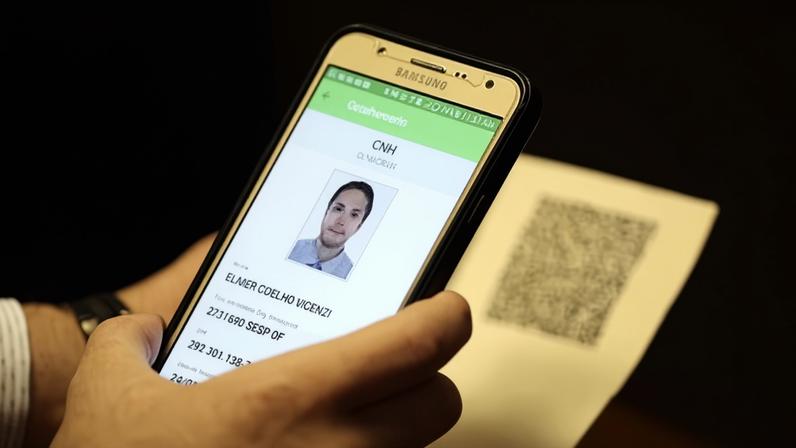 Mão segurando celular com CNH virtual
