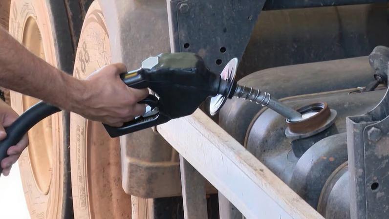 Pessoa abastecendo o tanque de combustível de um caminhão com uma bomba de diesel