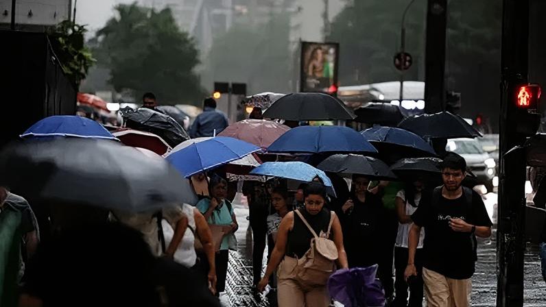 Pedestres se protegem da chuva durante temporal em São Paulo