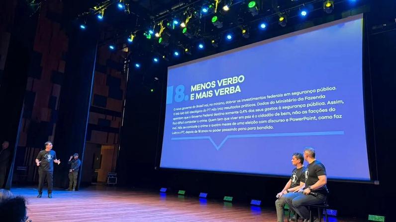 Em pé, o pré-candidato à Presidência Flávio Bolsonaro (PL) apresenta os 12 itens do plano de segurança. (Foto: Luisa Purchio/Gazeta do Povo)