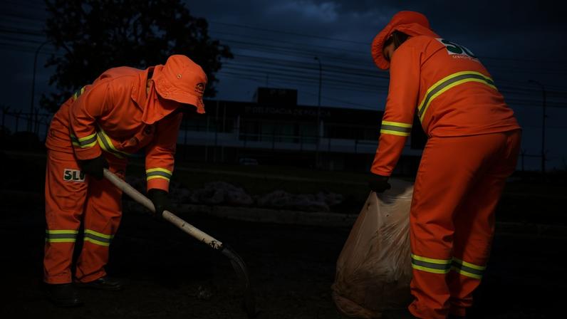 Servidores do SLU fazem a limpeza de asfalto queimado após manifestações de bolsonaristas na Asa Norte do dia de ontem. Na imagem, dois garis limpam local próxima à 5º Delegacia de Polícia Civil do DF - Metrópoles