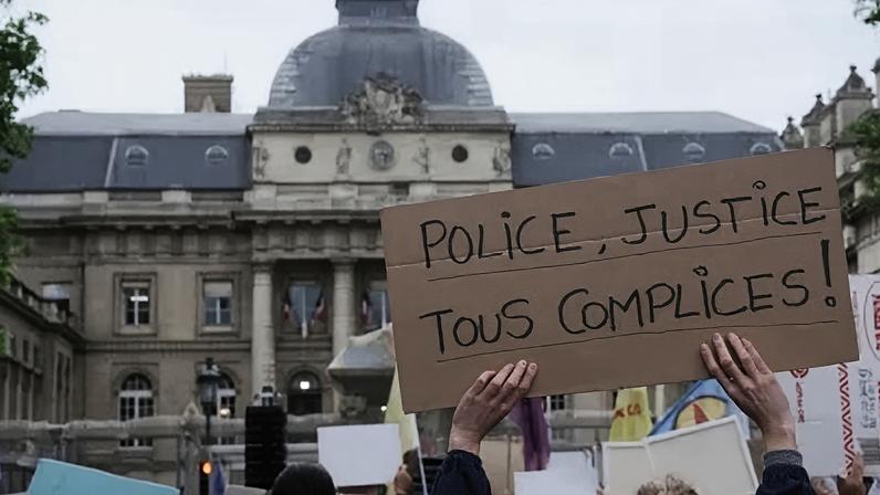 Placa com a frase: "Polícia, sistema judiciário, todos cúmplices" - durante protesto na França