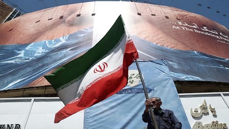 Homem segura bandeira iraniana perto de outdoor anti-EUA representando o presidente dos EUA, Donald Trump, e o Estreito de Ormuz, em Teerã, Irã, em 30 de maio de 2026 Majid Asgaripour/WANA via REUTERS