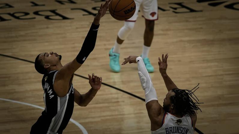 Victor Wembanyama attempts to block a shot attempt by Jalen Brunson