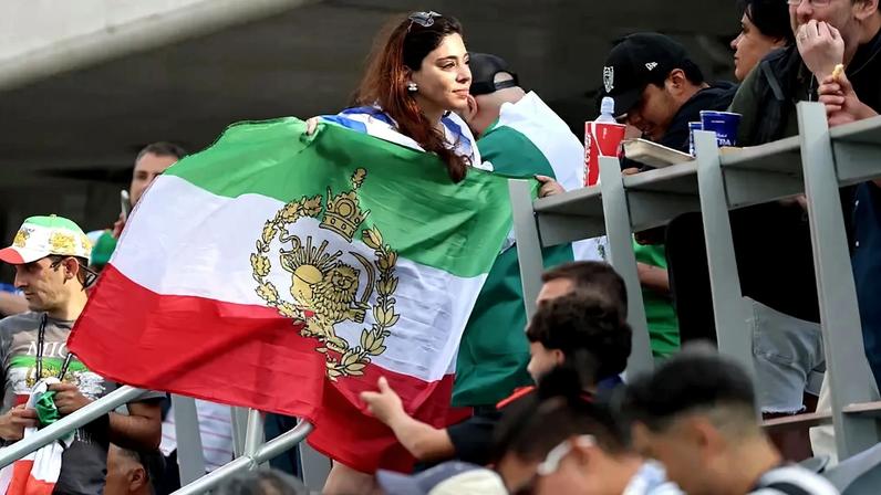 Torcedora do Irã no estádio de Los Angeles ostenta a bandeira símbolo da luta contra os aiatolás