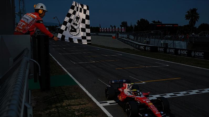 O vencedor da corrida, Lewis Hamilton, da Grã-Bretanha, pilotando o (44) Scuderia Ferrari SF-26, recebe a bandeira quadriculada durante o Grande Prêmio de Fórmula 1 de Barcelona-Catalunha