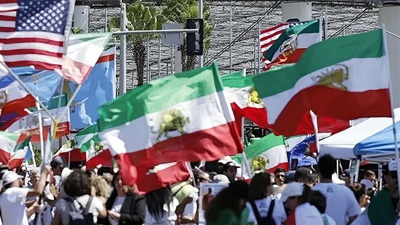 Manifestantes protestam contra a República Islâmica do Irã, exibindo bandeiras iranianas pré-revolucionárias e outras bandeiras, em frente ao Estádio de Los Angeles, nesta segunda-feira (15)