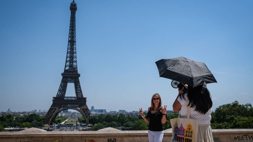Turistas se protegem do sol próximo à Torre Eiffel, em Paris, durante onda de calor que atingiu a Europa, nesta quarta-feira (24)