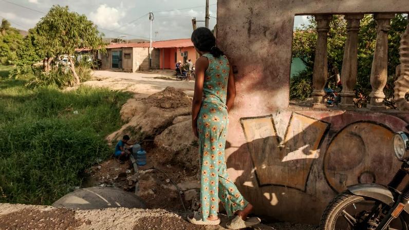 Em Cumaná, Venezuela, em 13 de maio de 2026, pessoas se reúnem ao redor de um riacho poluído para encher recipientes com água