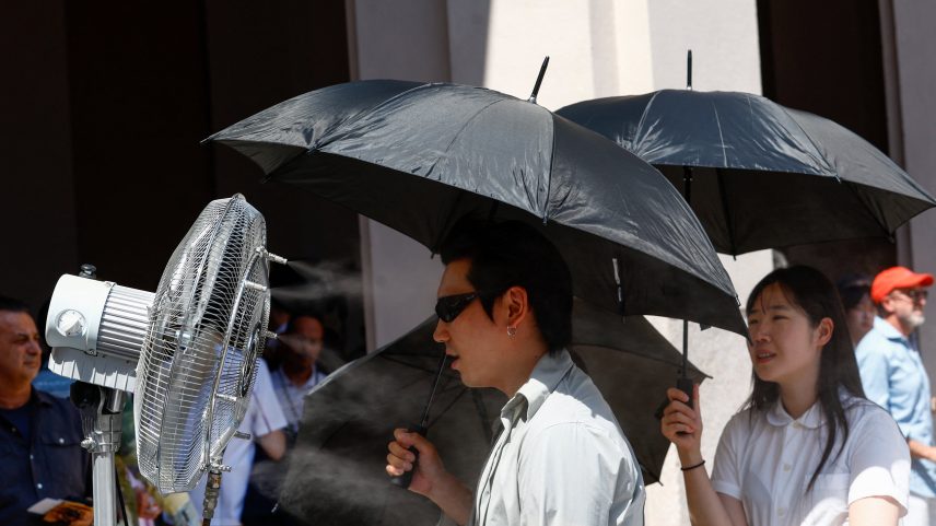 Pessoas tentam se proteger do sol enquanto ventilador borrifa água antes do desfile na Semana de Moda de Milão