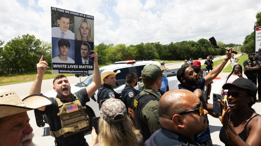 McKINNEY, TEXAS - JUNE 4: Pardoned U.S. Capitol rioter Jake Lang holds a sign that reads White Lives Matter with a photo of Austin Metcalf as police block supporters of Karmelo Anthony from approaching him outside of the Collin County Courthouse as Anthony's murder trial is underway in McKinney, TX, Thursday, June 4, 2026. Anthony is accused of killing 17-year-old Austin Metcalf last April at a Frisco track meet at David Kuykendall Stadium. (Juan Figueroa/The Dallas Morning News via Getty Images)
