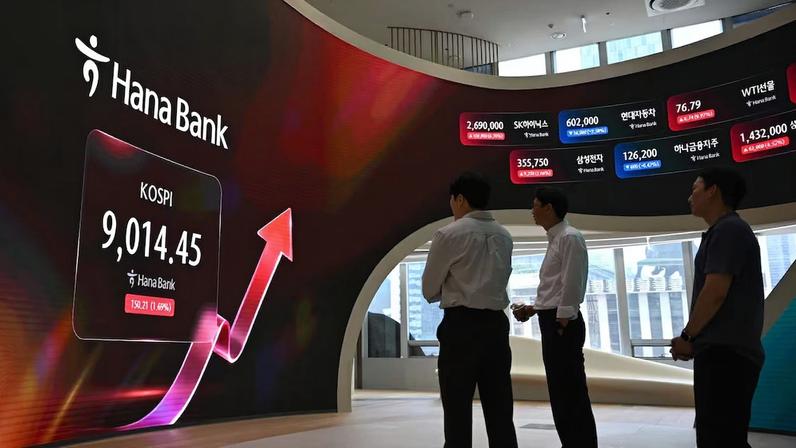Operadores de câmbio observam uma tela que exibe o principal índice de ações da Coreia do Sul (KOSPI) ultrapassando a marca de 9.000 pontos, em uma sala de operações da sede do Hana Bank, em Seul, em 18 de junho de 2026. O índice de referência Kospi, da Coreia do Sul, superou os 9.000 pontos pela primeira vez em 18 de junho, impulsionado por uma alta do setor de tecnologia liderada pelas gigantes de chips Samsung e SK hynix. Foto: Jung Yeon-je/AFP