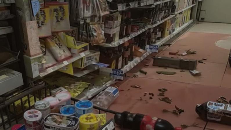 Interior de um supermercado ou loja de conveniência, com prateleiras cheias de produtos embalados, muitos deles com rótulos em japonês.