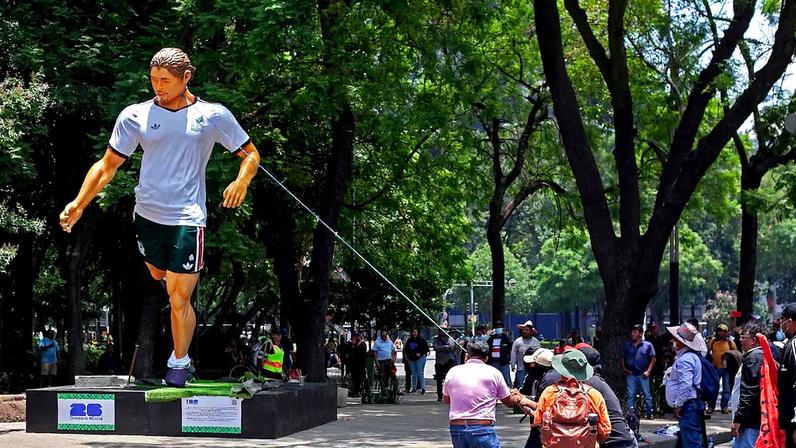 Manifestantes tentam derrubar estátua de jogador exposta no México.