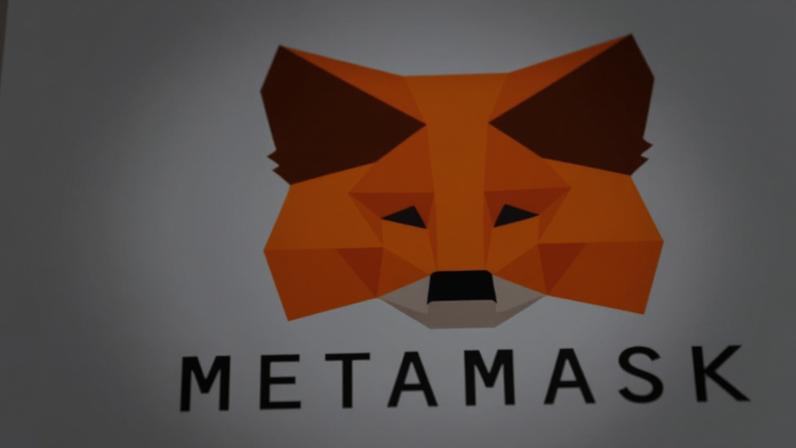 Mão segurando celular com o logo da carteira de criptomoedas MetaMask