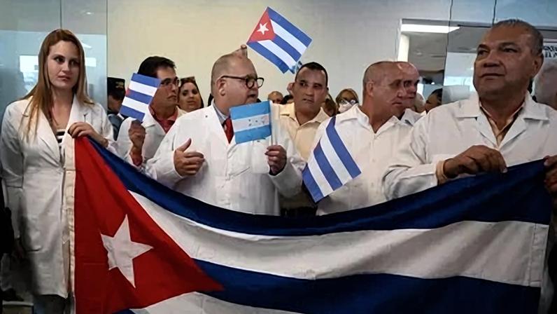 Médicos cubanos seguram uma bandeira nacional ao chegarem ao Aeroporto Internacional de Palmerola em 27 de fevereiro de 2024