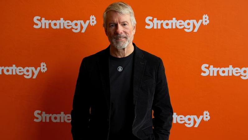 Michael Saylor posa para foro à frente do logo da Strategy
