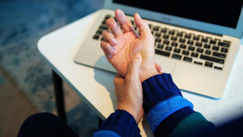 Cropped image of an Asian woman massaging her arthritic hand and wrist after long hours in front of a computer...
