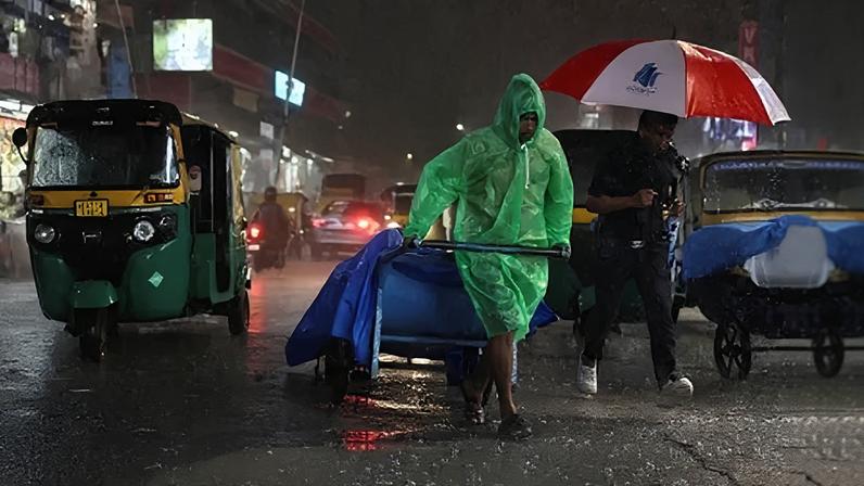 Um homem puxa um carrinho cheio de mercadorias durante a chuva em Bengaluru 3 de setembro de 2025 REUTERS/Priyanshu Singh