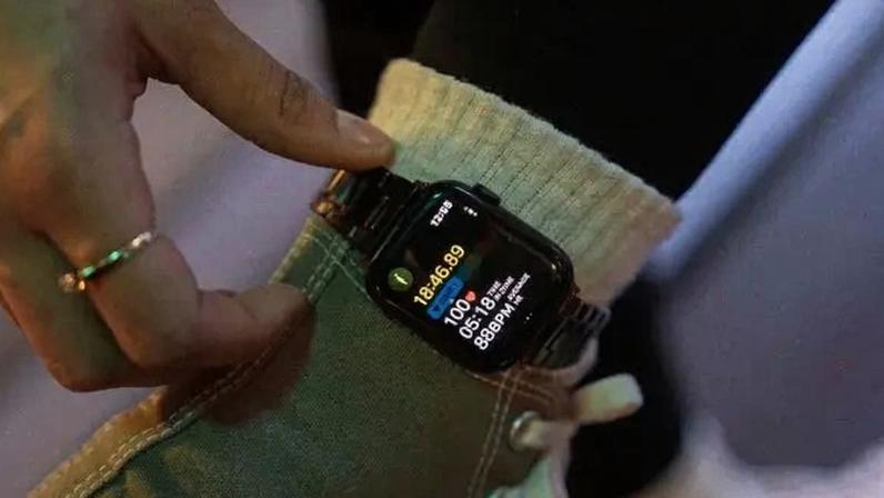 Closeup of an Apple Watch being worn around a woman's ankle as she exercises. A hand is reaching to adjust the watch.