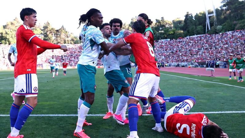 Rafael Leão, de branco e à esquerda, observa o jogador do Chile caído após soco