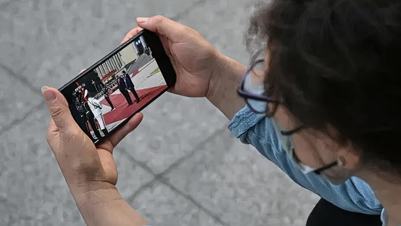 Getty Images A woman watches a video of US President Donald Trump with China's President Xi Jinping on a mobile phone in Beijing, in May this year