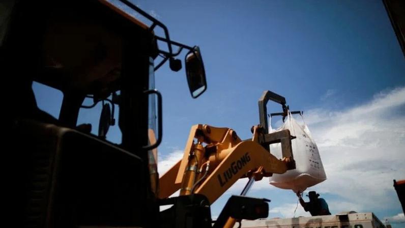 Um trabalhador rural carrega fertilizante em um trator antes de espalhá-lo em um campo de soja, perto de Brasília (DF)