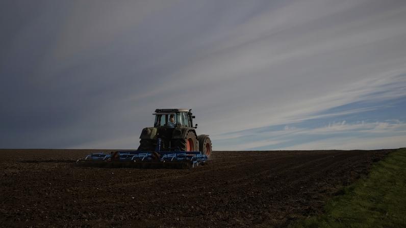 Na imagem, uma máquina agrícola no meio do campo