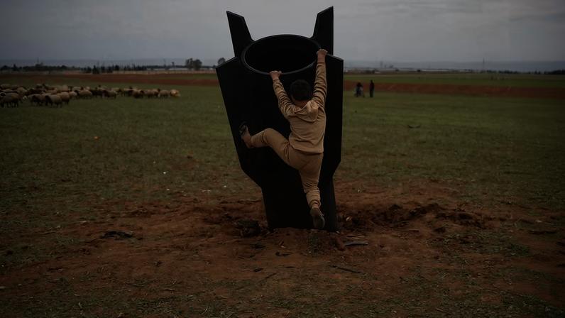 Menino tenta subir em um projétil iraniano não detonado que caiu em um campo aberto nos arredores de Qamishli, no leste da Síria, na quarta-feira, 4 de março de 2026. — Foto: Baderkhan Ahmad/AP