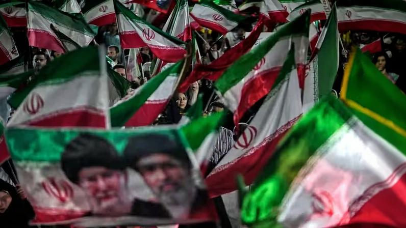 Manifestantes pró-governo iranianos agitam bandeiras do Irã e um retrato do Líder Supremo, Aiatolá Mojtaba Khamenei (à direita), e de seu falecido pai, Aiatolá Ali Khamenei, em uma reunião em uma praça em Teerã, Irã, na sexta-feira, 29 de maio de 2026 — Foto: AP/Vahid Salemi