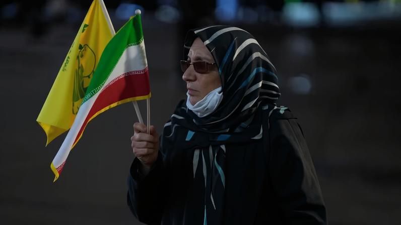 Uma mulher segura uma bandeira iraniana e uma bandeira do grupo militante libanês Hezbollah durante uma manifestação pró-governo na Praça da Revolução Islâmica em Teerã, Irã, sábado, 30 de maio de 2026 — Foto: AP/Vahid Salemi