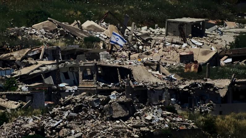 Uma bandeira israelense tremula em um prédio destruído no sul do Líbano, vista do norte de Israel — Foto: AP/Ariel Schalit