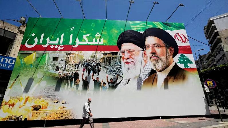 Homem passa por outdoor que mostra fotos do ex-líder iraniano Ali Khamenei e o atual líder supremo, aiatolá Mojtaba Khamenei, com os dizeres em árabe 'Obrigado, Irã', em Dahiyeh, no sul de Beirute, capital do Líbano, no dia 15 de junho de 2026 — Foto: Hussein Malla/AP