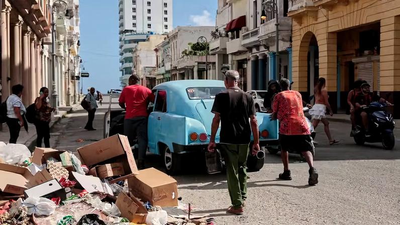 Várias pessoas empurram um carro clássico quebrado ao lado de um monte de lixo em Havana, Cuba, na quarta-feira, 17 de junho de 2026 — Foto: AP Foto/Jorge Luis Banos
