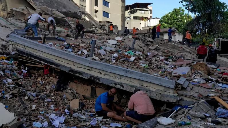 Moradores e equipes de resgate vasculham os escombros de um prédio que desabou durante os terremotos que atingiram Caracas, Venezuela, na quinta-feira, 25 de junho de 2026