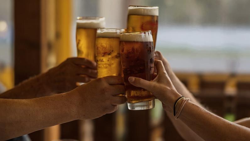 Grupo de 4 pessoas brinda com copos de cerveja - Metrópoles