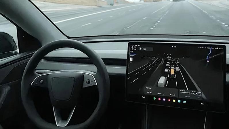 Getty Images A black steering wheel and large screen to the right which shows lanes of traffic and vehicles in it.