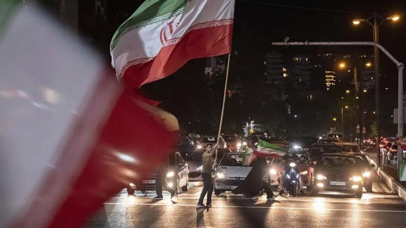 Um apoiador do governo agita uma bandeira nacional iraniana gigante durante um protesto noturno no norte de Teerã, Irã, em 8 de junho de 2026. O protesto é realizado em apoio às recentes operações militares do Irã, que incluíram ataques com mísseis. (Foto de Morteza Nikoubazl/NurPhoto via Getty Images)