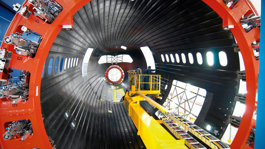 Boeing assembles a composite aircraft fuselage section in one of its production facilities. Composite materials are used in major portions of modern aircraft, including sections of the fuselage and wings on aircraft such as the Boeing 787. NASA’s HiCAM project aims to help accelerate manufacturing processes for future composite aircraft.