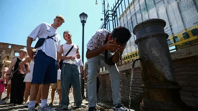 Uma pessoa se refresca em uma fonte pública próxima ao Coliseu durante uma onda de calor em Roma