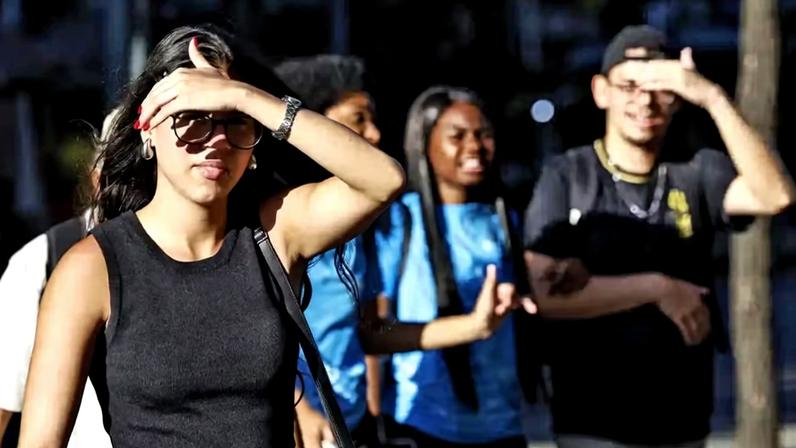 Pedestres se protegem do sol na região central do Rio de Janeiro durante onda de calor.