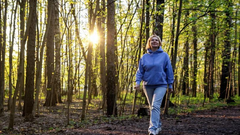 Mulher caminhando em um parque iluminado pelo sol ao pôr do sol na primavera - Metrópoles