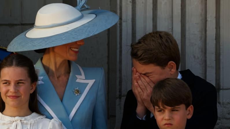 A Princesa Kate Middleton sorrindo enquanto o Príncipe George espirra, na bancada do Palácio de Buckingham, durante a edição de 2026 do desfile militar Trooping the Colour, em 13 de junho de 2026