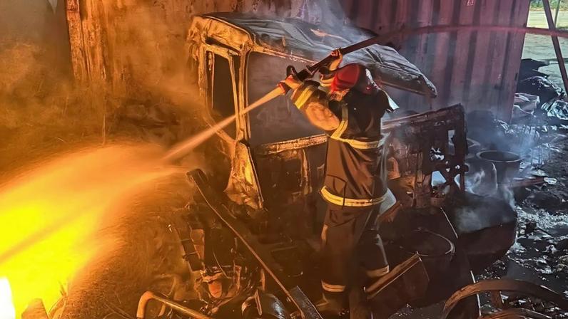 Bombeiros controlam incêndio em pátio de sucatas de caminhões em Lavras.