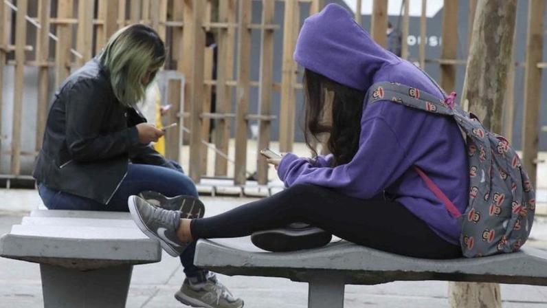 Na imagem, adolescentes de cabeça baixa utilizando o celular
