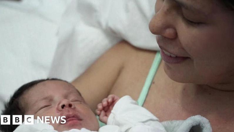 Dayana Patino looks down at her son Juan David smiling from a hospital bed Caracas. Both mother and baby have injuries on their faces