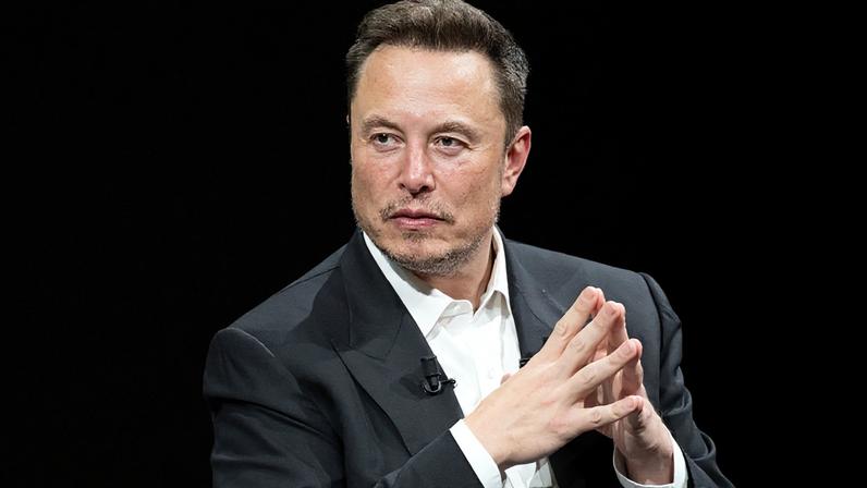 Elon Musk de paletó gesticula com as mãos